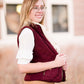 Woman wearing a cold weather, quilted puffer vest. This vest comes in mauve, black, navy and wine. It features pockets and a front zip.