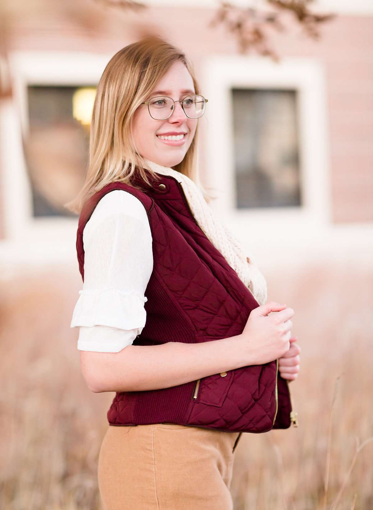 Woman wearing a cold weather, quilted puffer vest. This vest comes in mauve, black, navy and wine. It features pockets and a front zip.