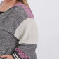 Plus size woman wearing a gray and purple hooded color block sweatshirt. It also has front pockets and banded wrist and waist.