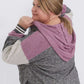 Plus size woman wearing a gray and purple hooded color block sweatshirt. It also has front pockets and banded wrist and waist.