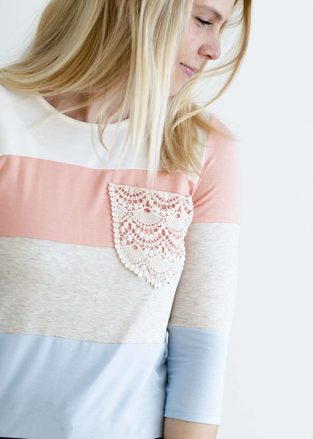 Woman wearing a modest peach, ivory, blue and navy 3/4 top with a lace pocket