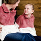 Young girl wearing a mauve and cream plush, sherpa style quarter zip sweater. This sweater has pockets and is paired with a long denim skirt. It is also a mommy and me style!