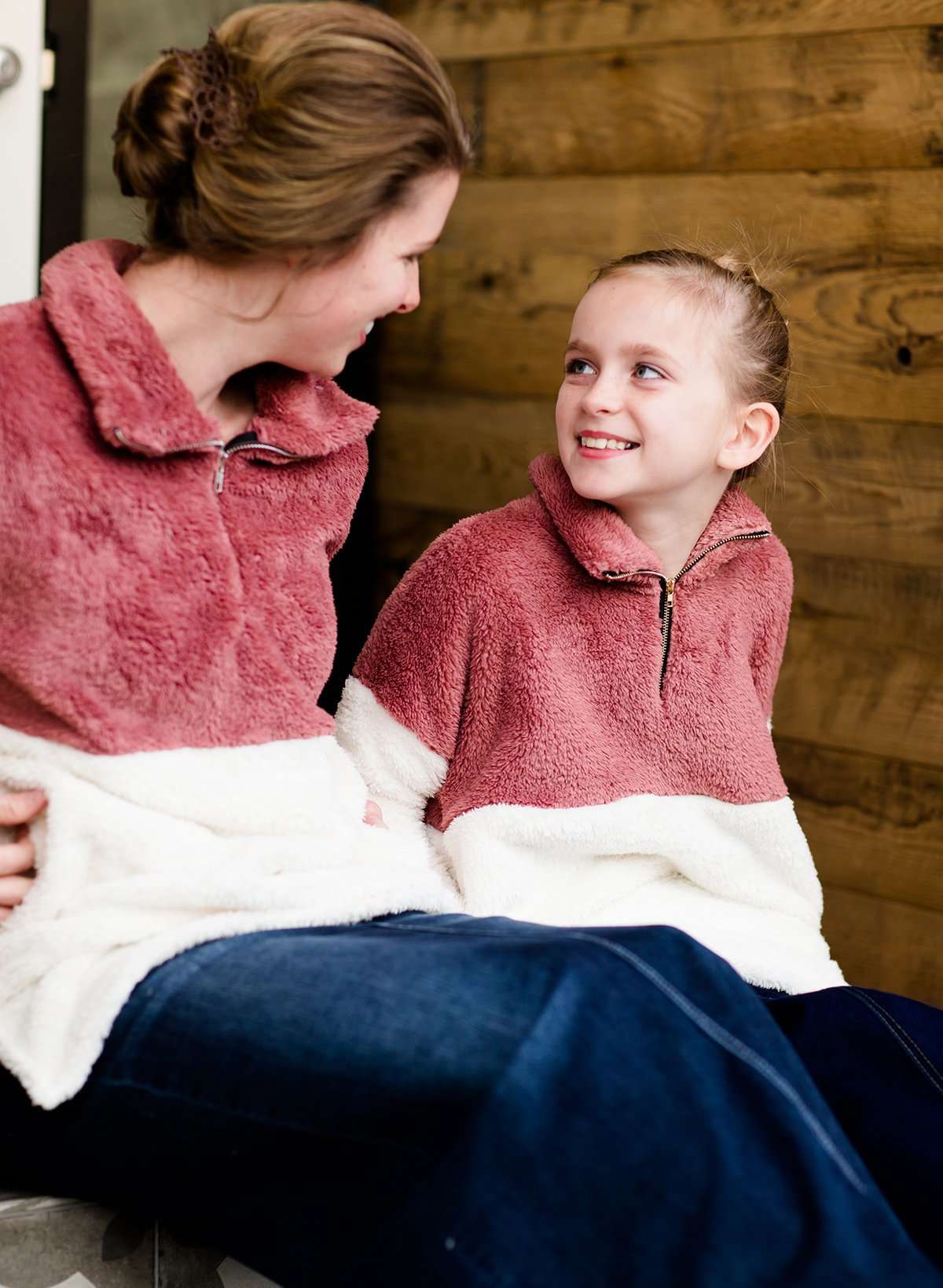 Young girl wearing a mauve and cream plush, sherpa style quarter zip sweater. This sweater has pockets and is paired with a long denim skirt. It is also a mommy and me style!