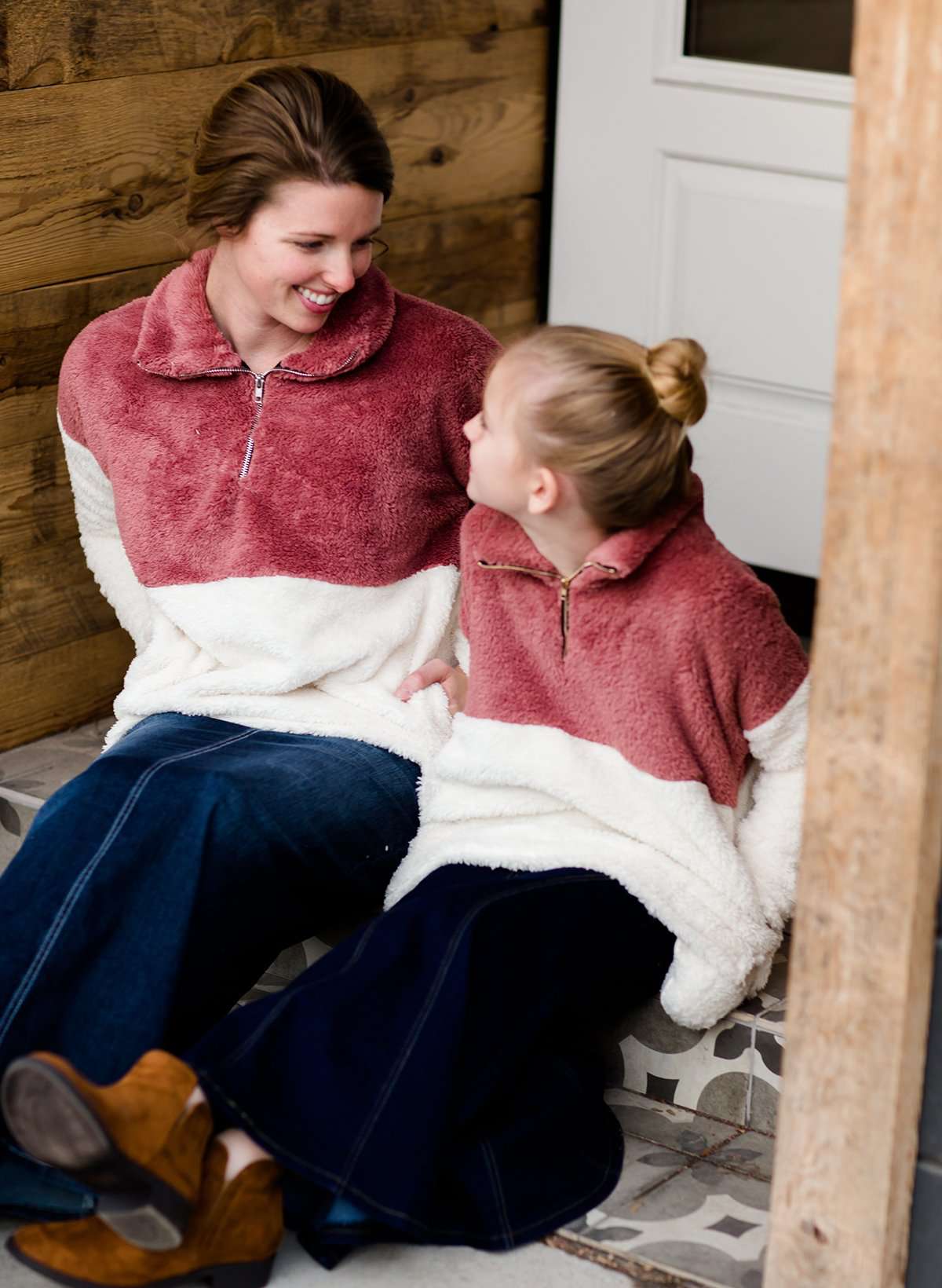 Young girl wearing a mauve and cream plush, sherpa style quarter zip sweater. This sweater has pockets and is paired with a long denim skirt. It is also a mommy and me style!