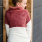 Young girl wearing a mauve and cream plush, sherpa style quarter zip sweater. This sweater has pockets and is paired with a long denim skirt. It is also a mommy and me style!