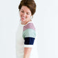 Woman wearing a modest white tee shirt with lavender, sage and navy stripes on the shoulders, tucked into a long denim modest skirt.