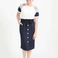 Woman wearing a navy button front paper bag style midi skirt.