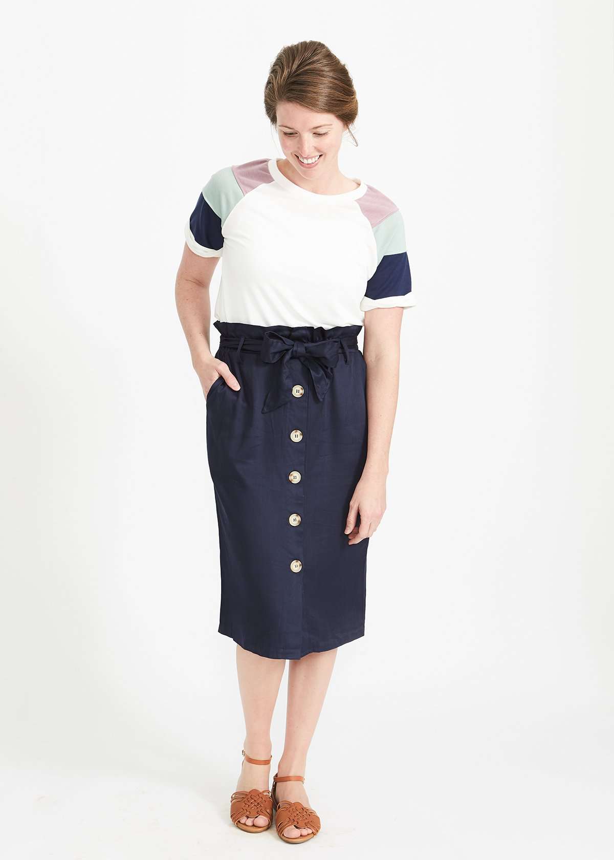Woman wearing a navy button front paper bag style midi skirt.