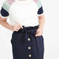 Woman wearing a navy button front paper bag style midi skirt.