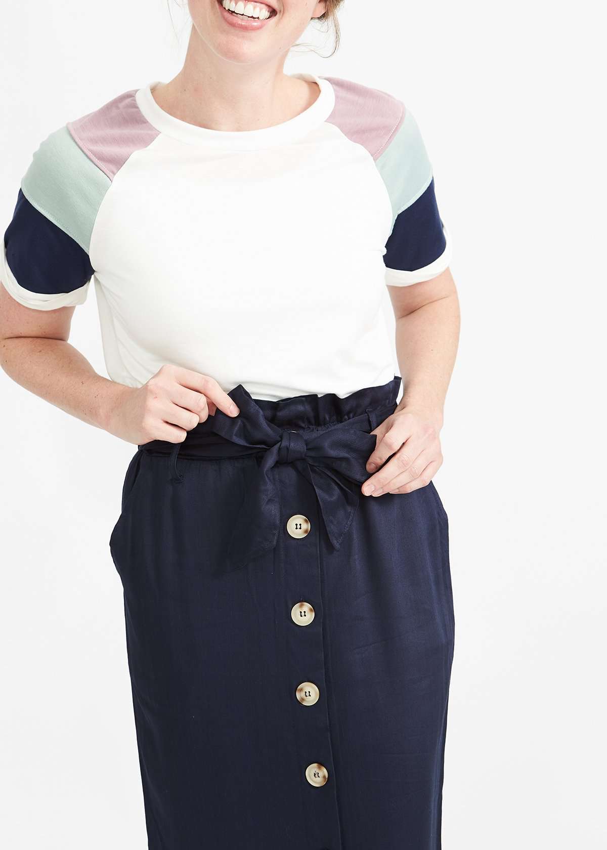 Woman wearing a navy button front paper bag style midi skirt.