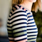 Woman wearing a striped top and solid hunter green bottom maxi dress.