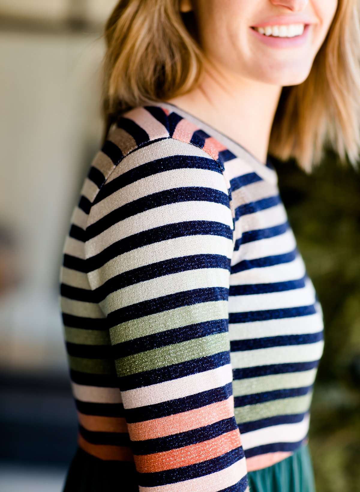 Woman wearing a striped top and solid hunter green bottom maxi dress.