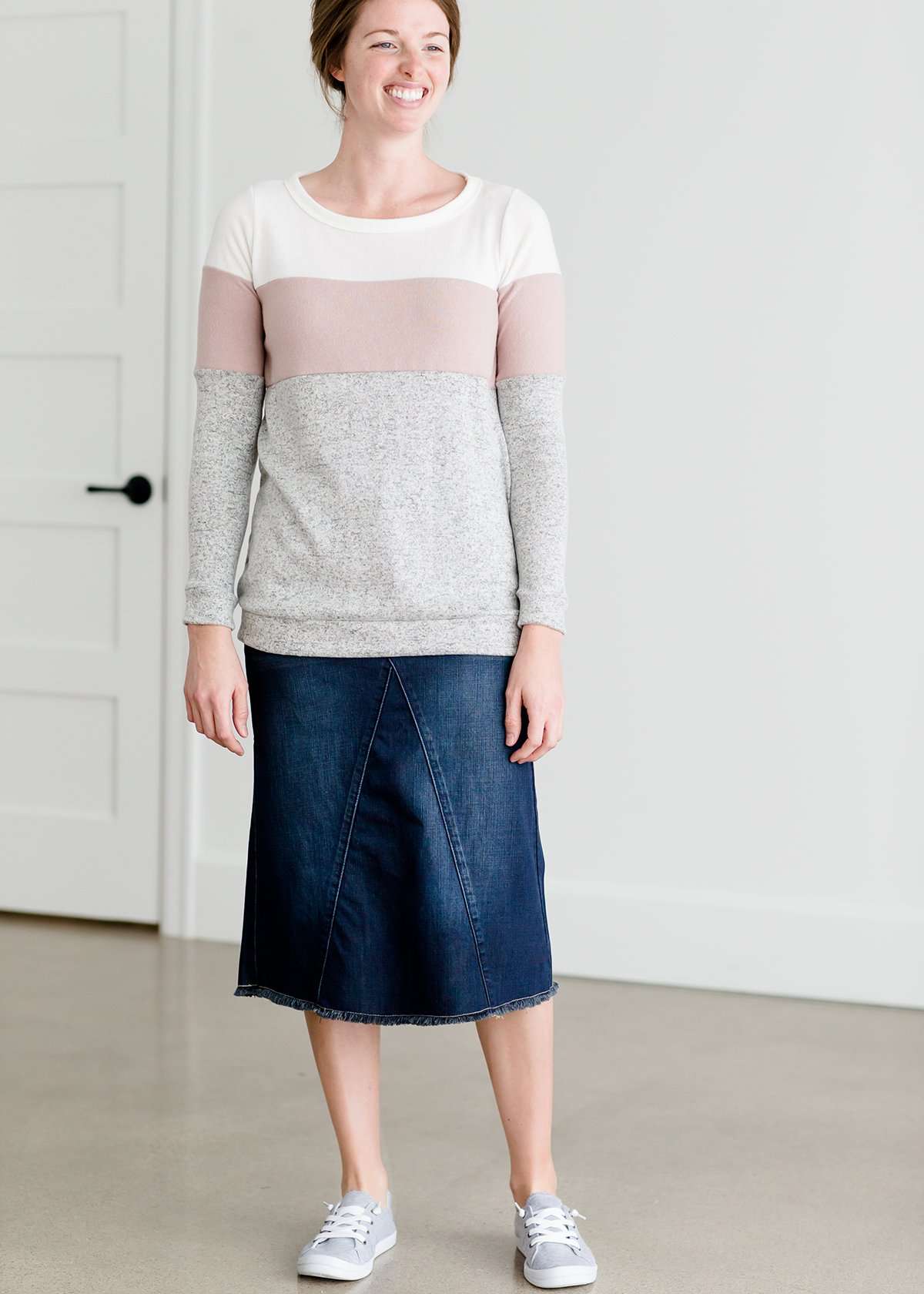 woman wearing a modest, soft sweater that is color blocked with white, mauve and gray.