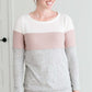 woman wearing a modest, soft sweater that is color blocked with white, mauve and gray.