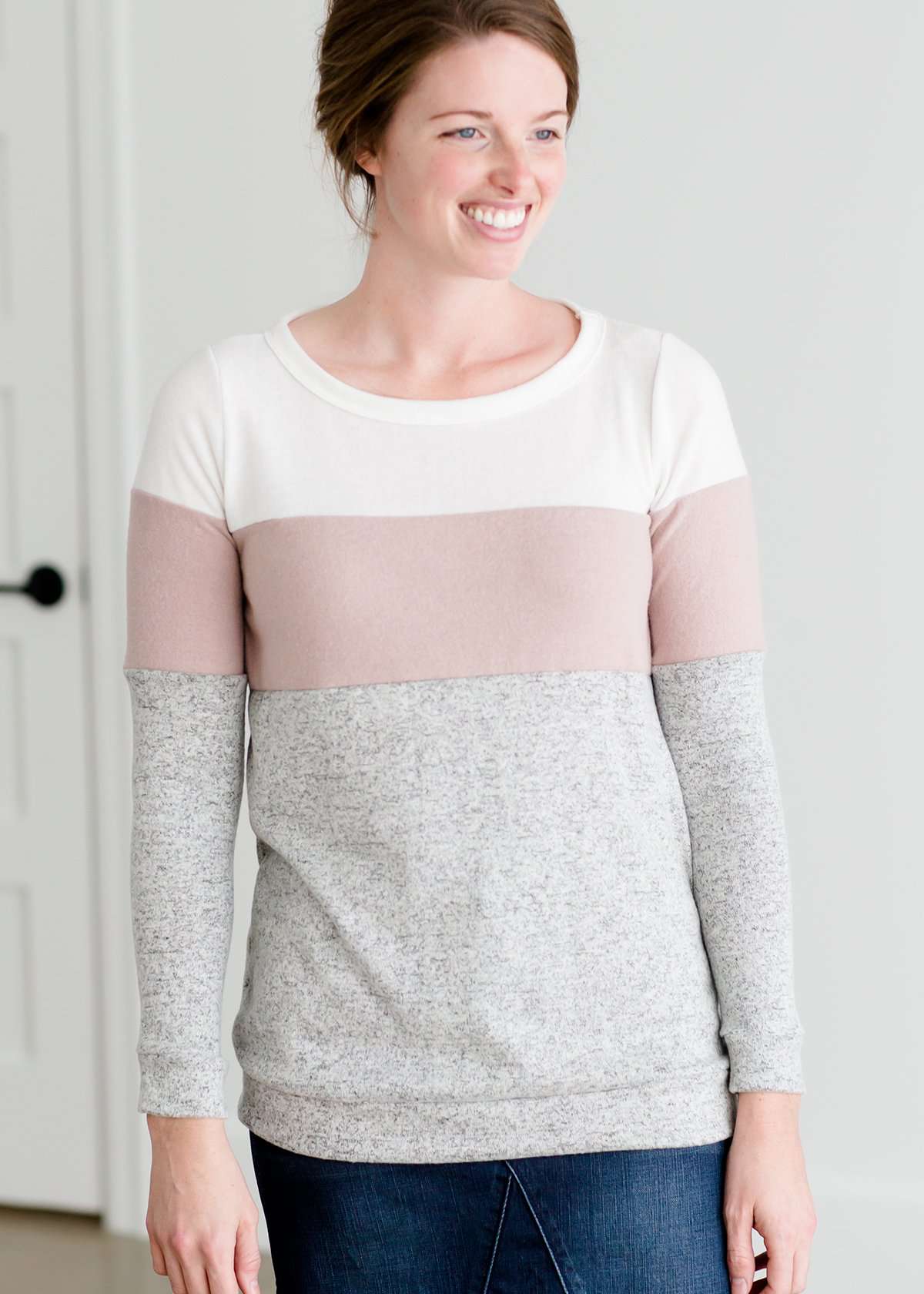 woman wearing a modest, soft sweater that is color blocked with white, mauve and gray.