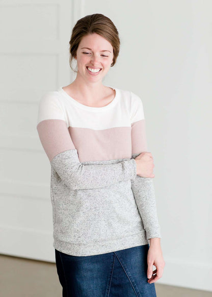 woman wearing a modest, soft sweater that is color blocked with white, mauve and gray.