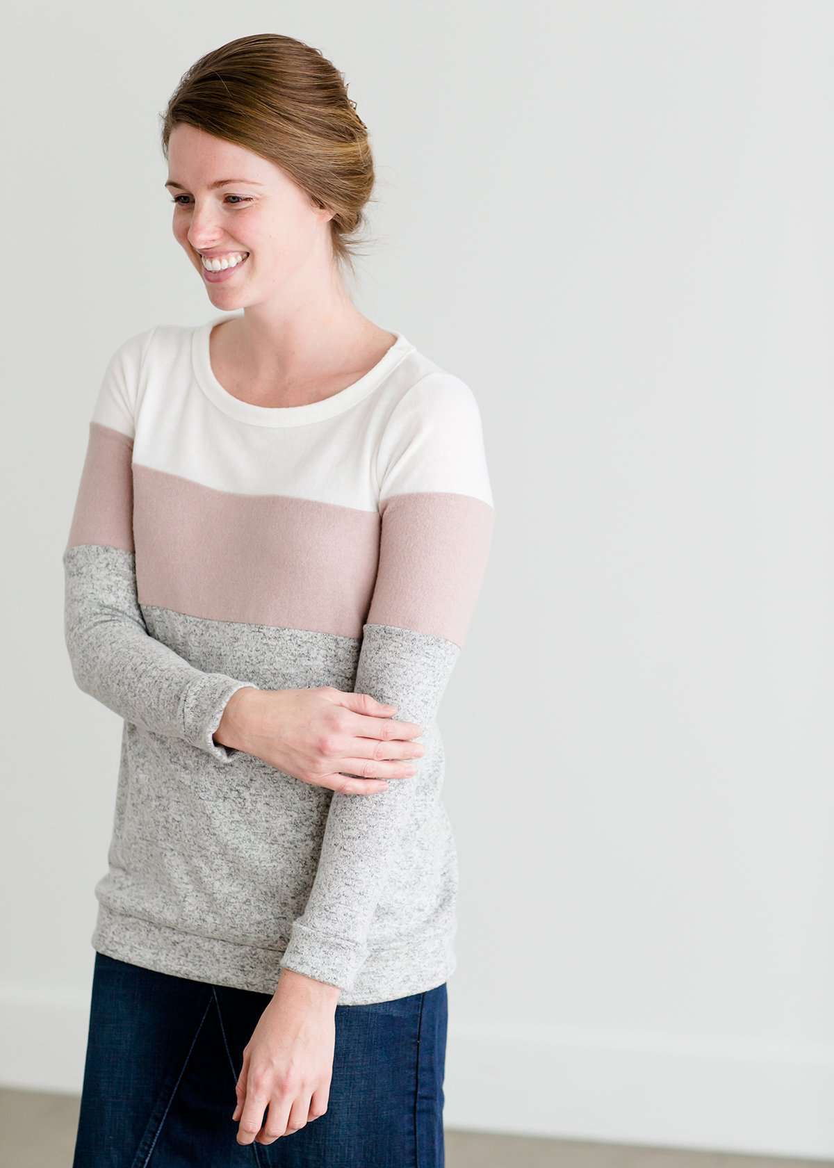 woman wearing a modest, soft sweater that is color blocked with white, mauve and gray.