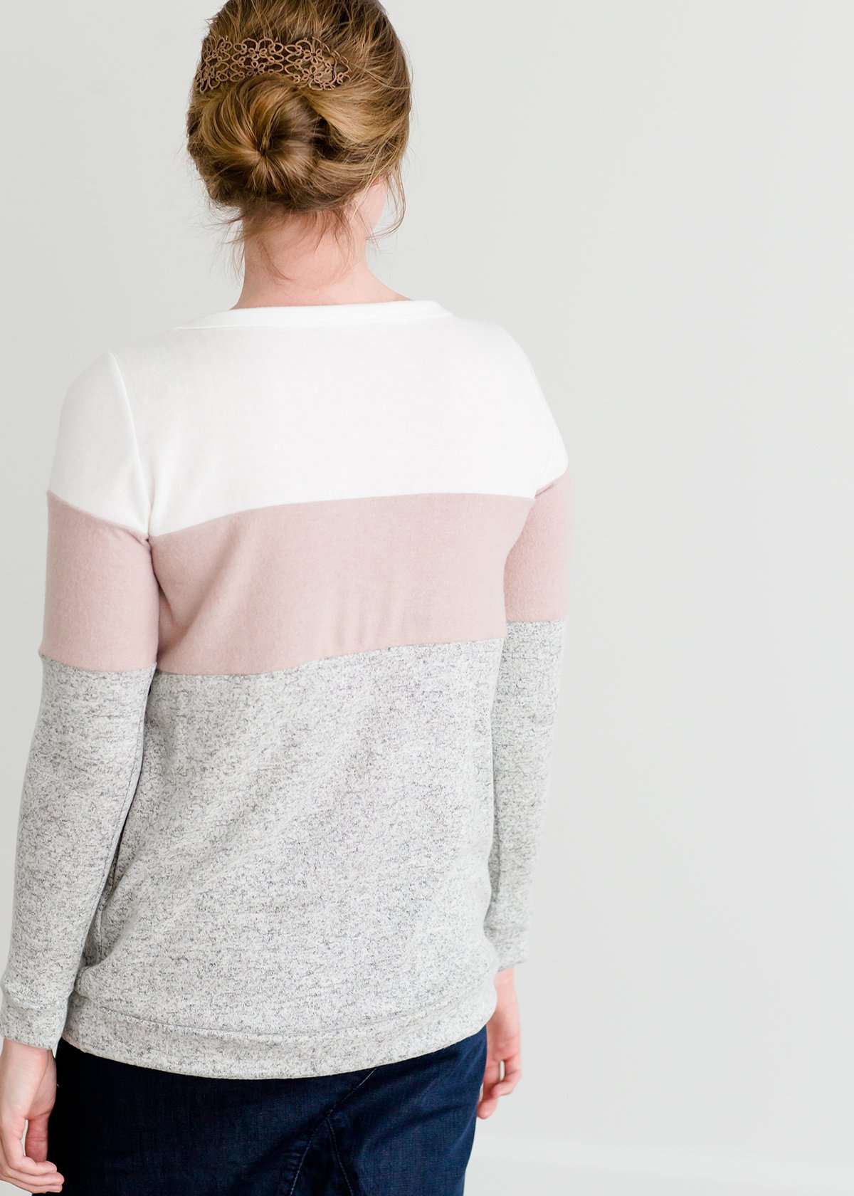 woman wearing a modest, soft sweater that is color blocked with white, mauve and gray.