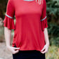 Woman wearing a rust colored, modest bell sleeve top. The 3/4 sleeves flutter and the top is also lined.