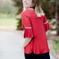 Woman wearing a rust colored, modest bell sleeve top. The 3/4 sleeves flutter and the top is also lined.