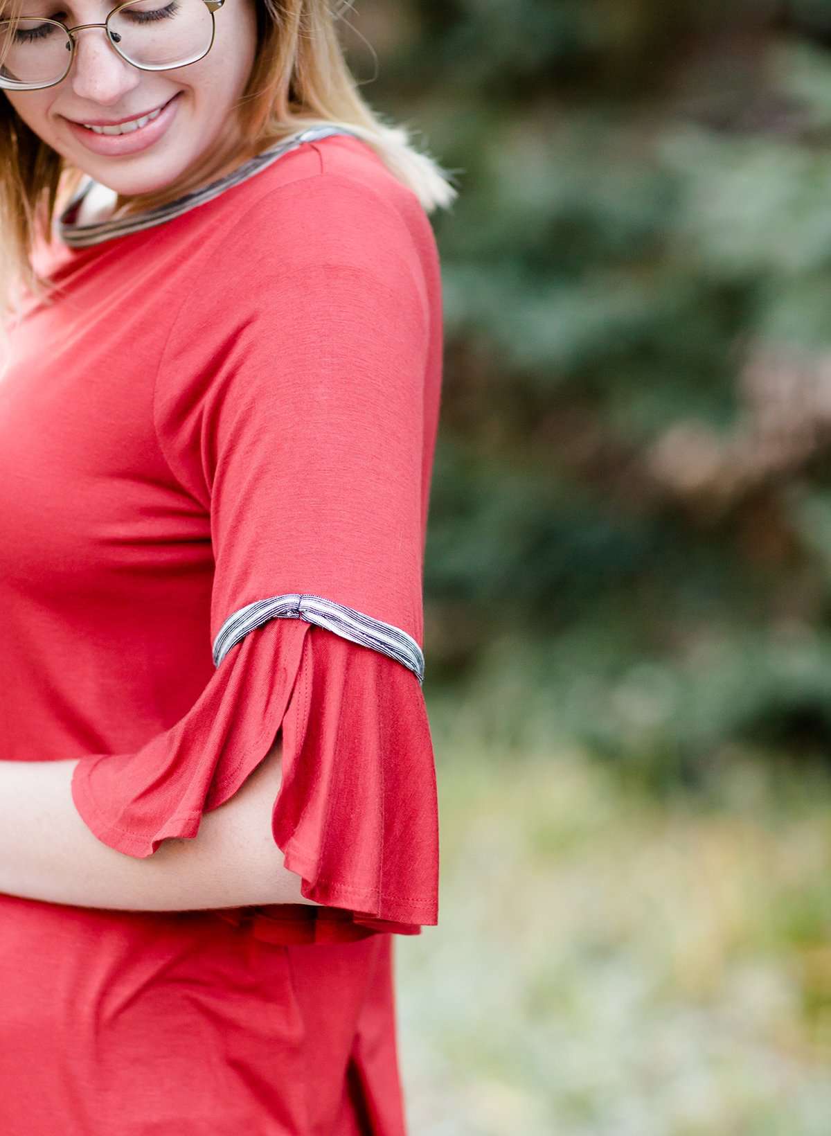 Woman wearing a rust colored, modest bell sleeve top. The 3/4 sleeves flutter and the top is also lined.