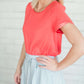 modest coral blouse with a different shade coral at the end hem of the sleeve.