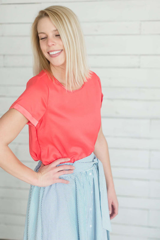 modest coral blouse with a different shade coral at the end hem of the sleeve.