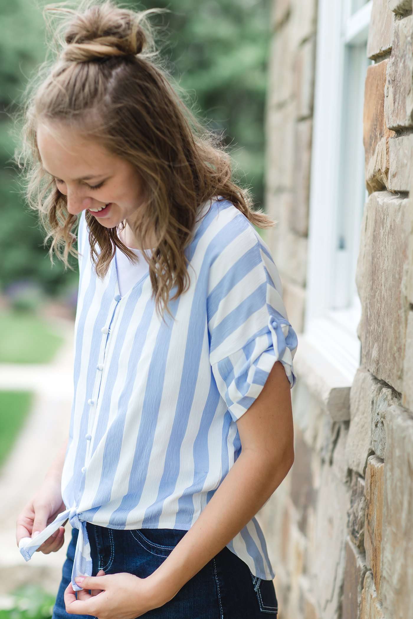 Blue and white vertical stripe top with short roll up sleeves and a tie front. Buttons up the front to a v-neck.