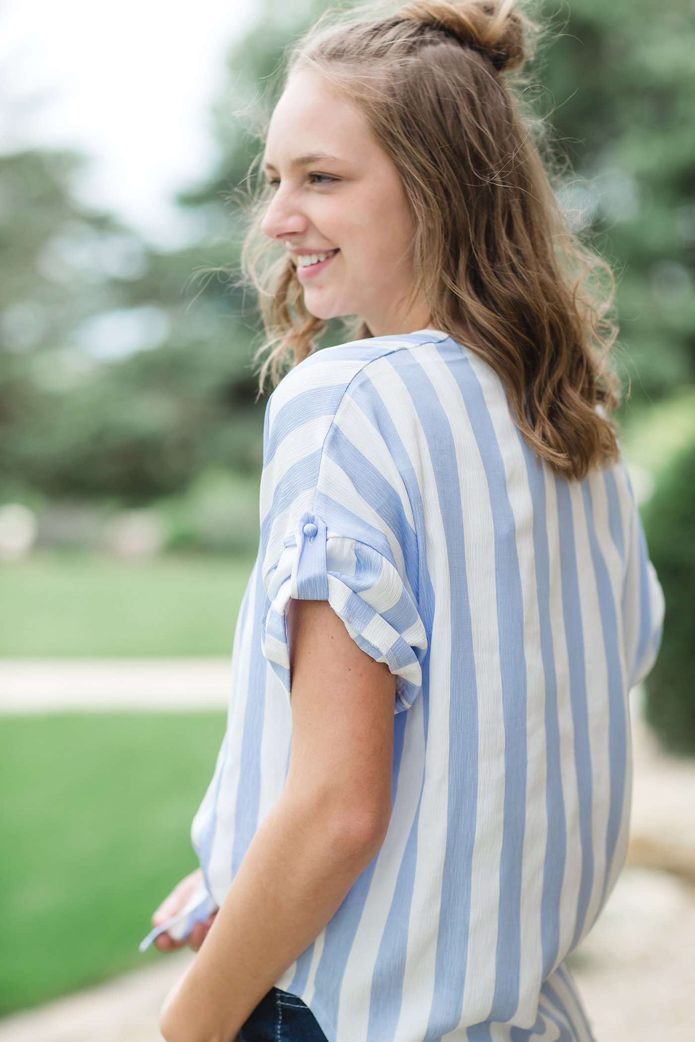 Blue and white vertical stripe top with short roll up sleeves and a tie front. Buttons up the front to a v-neck.