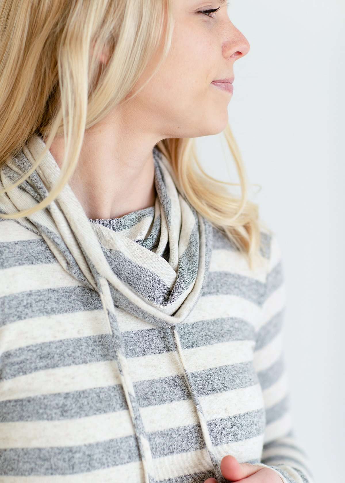 Woman wearing a modest gray and white striped cowl neck pullover top.