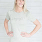 Grey and white striped crew neck tee shirt with a ruffle just above the chest.