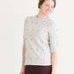 Woman wearing a gray crew neck sweatshirt that is half sleeves and has jewel designs on it.