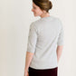 Woman wearing a gray crew neck sweatshirt that is half sleeves and has jewel designs on it.