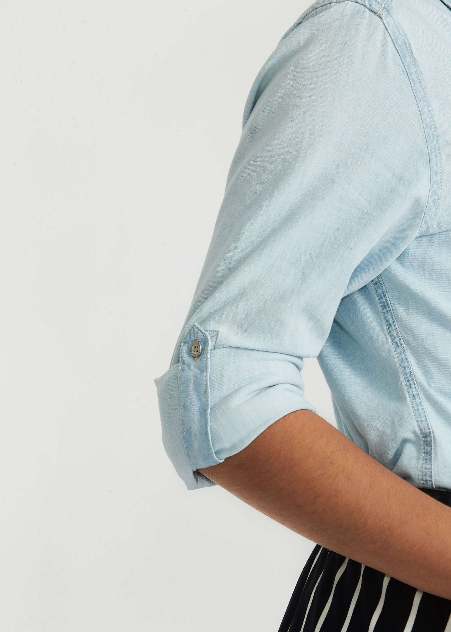 Light colored denim button down shirt, three quarter length sleeve with two front pockets and collar.