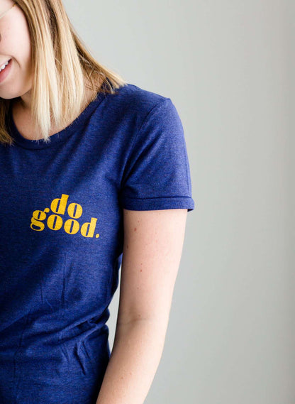 Young woman wearing a blue graphic tee with yellow words that says "Do Good." It is also paired with a below the knee denim skirt and a plaid button up top.