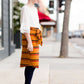 Young girl wearing an ivory, oversized modest top with ruffle sleeve accents. This top is also paired with a mustard, striped below the knee skirt and short boots.