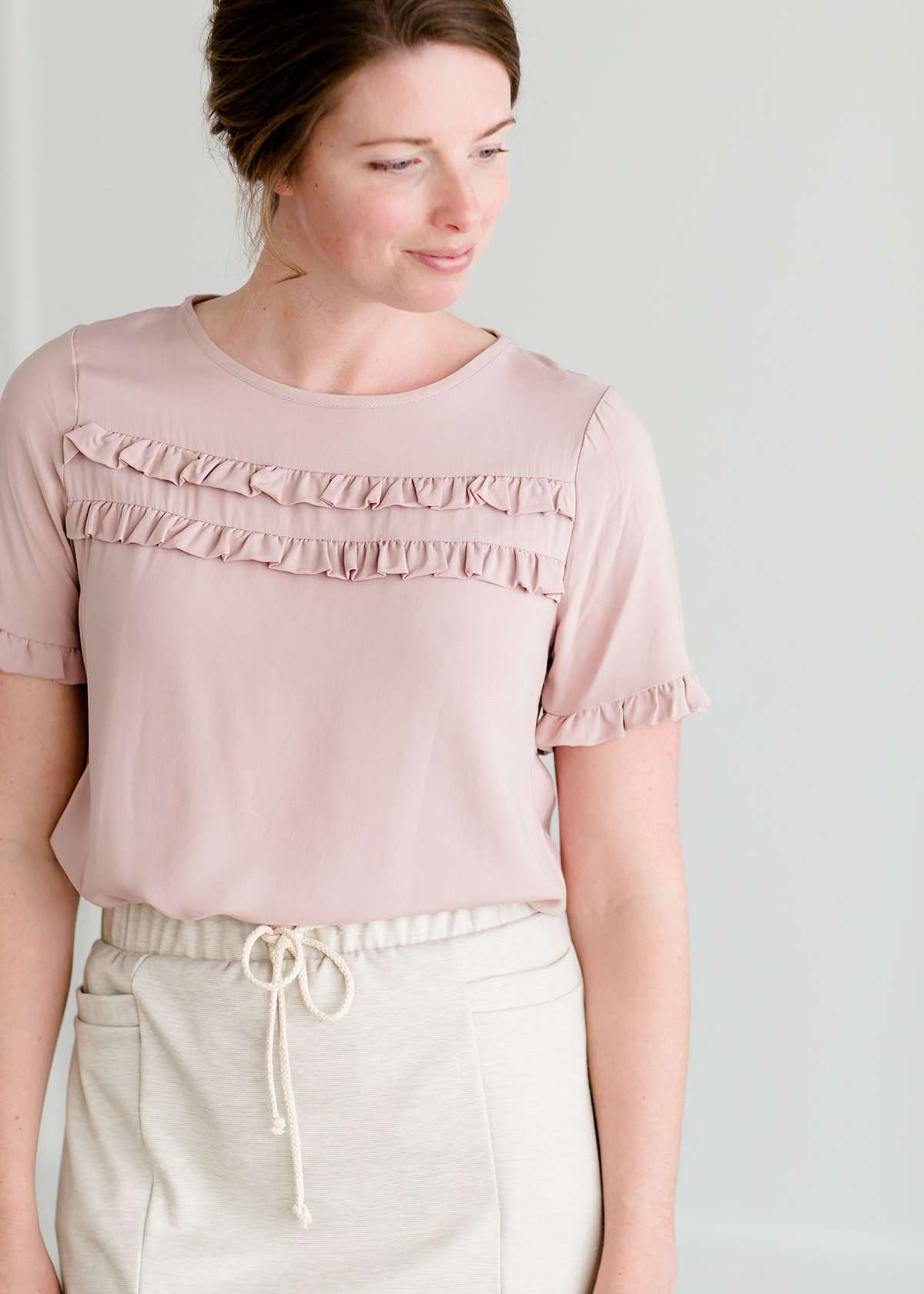 Woman wearing a modes blush double ruffle top with ruffles on the sleeves.