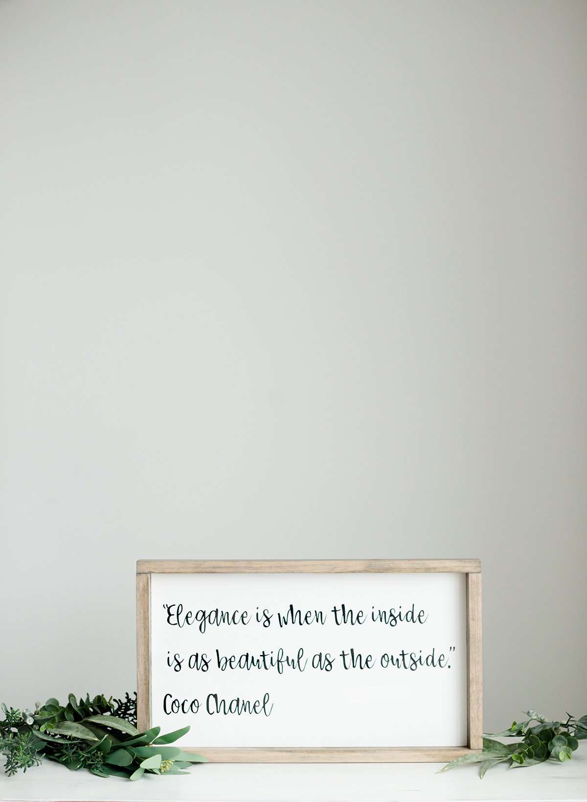 Woodframe Signboard that has script writing that says " Elegance is when the inside is as beautiful as the outside." by Coco Chanel