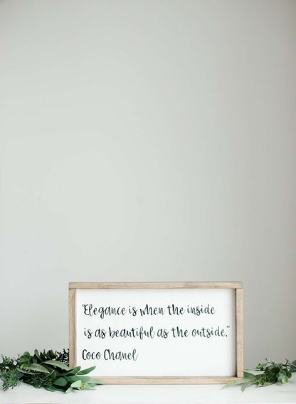 Woodframe Signboard that has script writing that says " Elegance is when the inside is as beautiful as the outside." by Coco Chanel