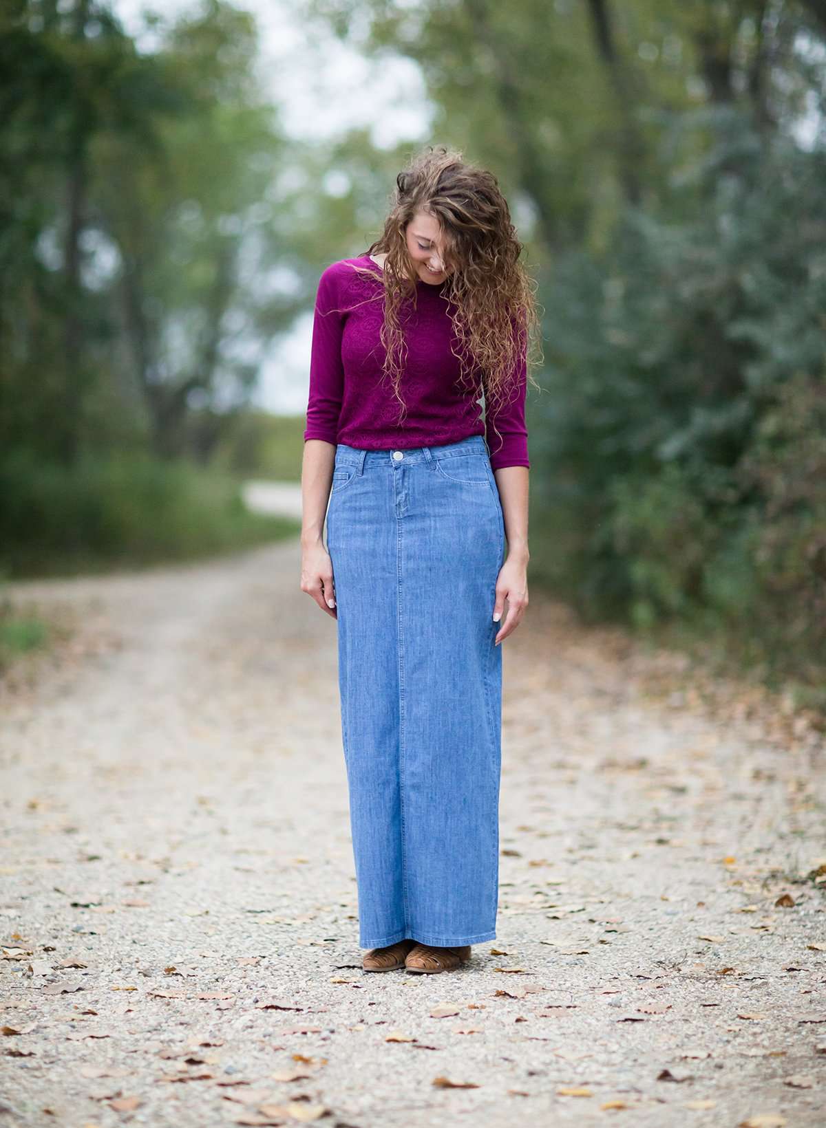 Woman on a gravel road wearing a long denim modest jean skirt