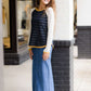 Woman wearing a long denim modest jean skirt. She is wearing a long sleeve, navy raglan top and standing outside of Inherit Clothing Company