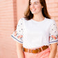 White top with multi color floral embroidered knit sleeves