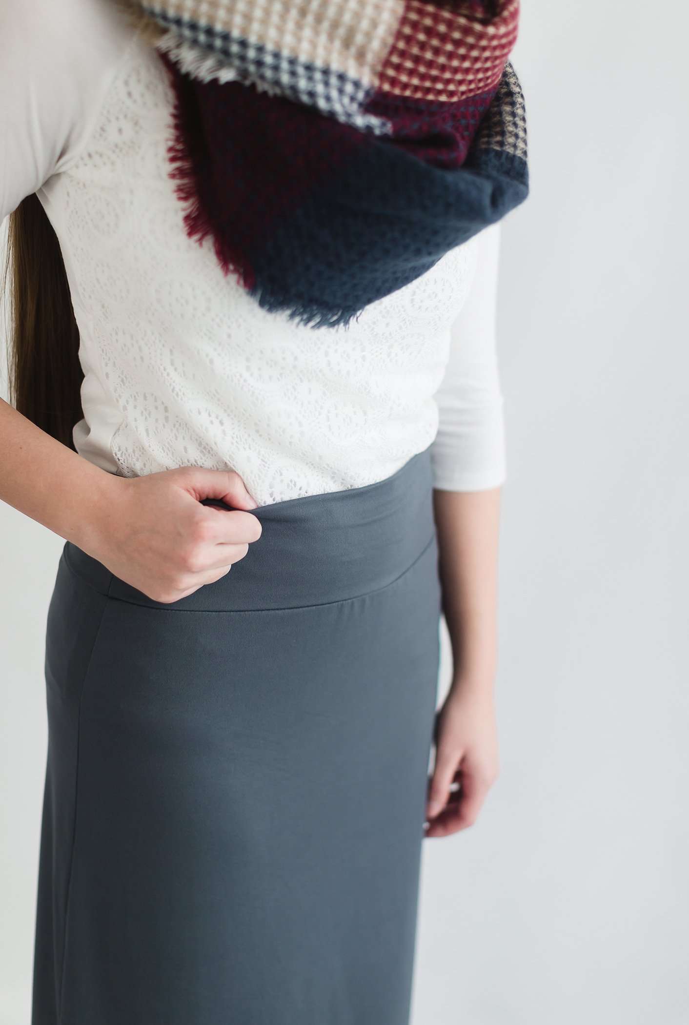 Woman wearing a midi skirt in black, olive, charcoal and Burgundy