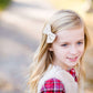 Young girl wearing a cream colored faux fur vest. It is a modest layering vest that also features beaded detail