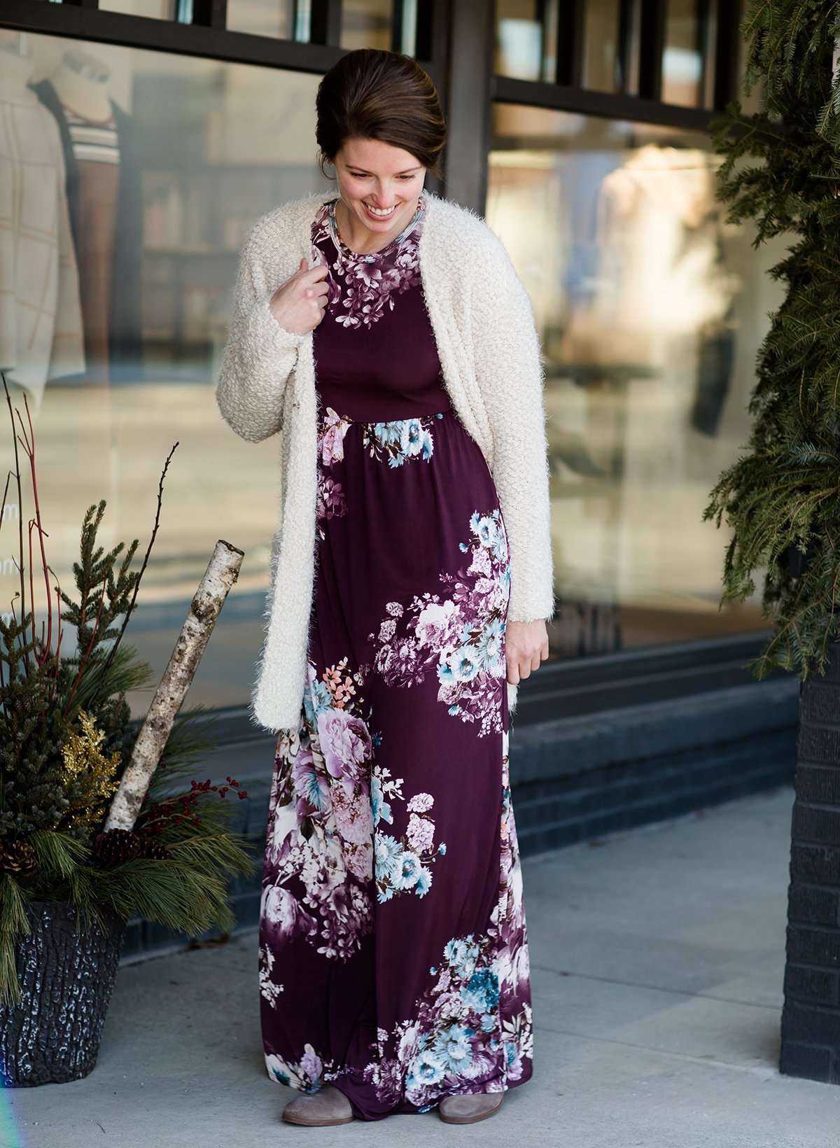 Woman wearing a modest, plum and navy maxi dress that has a elegant, floral print.