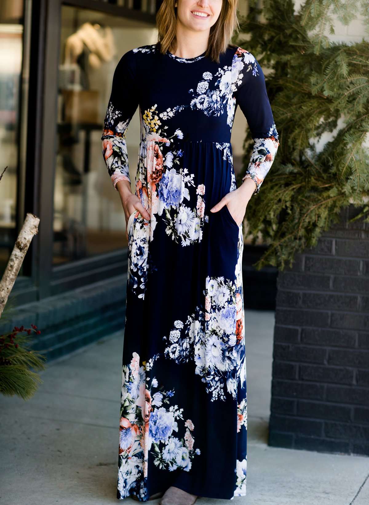 Woman wearing a modest, plum and navy maxi dress that has a elegant, floral print.