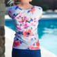 Woman by pool wearing a gray and floral modest swimsuit top