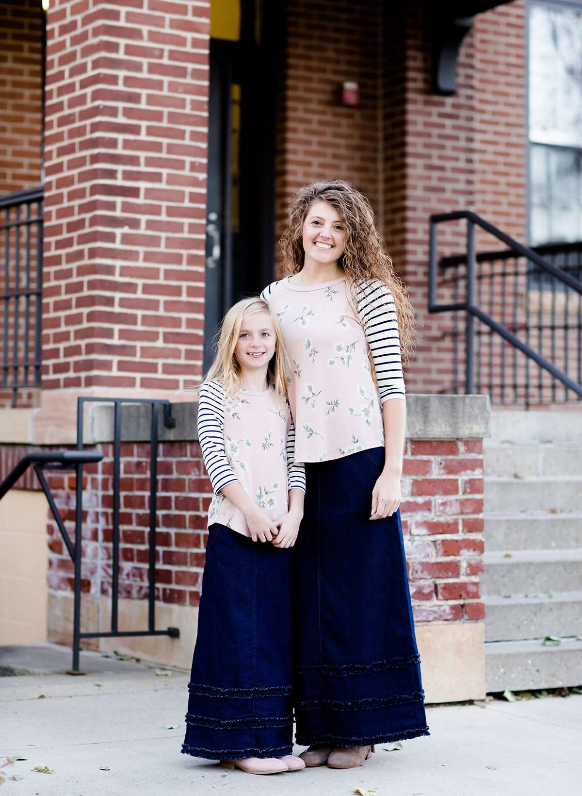 Young girl and her mother wearing a mommy and me a floral and striped contrast baseball style modest shirt