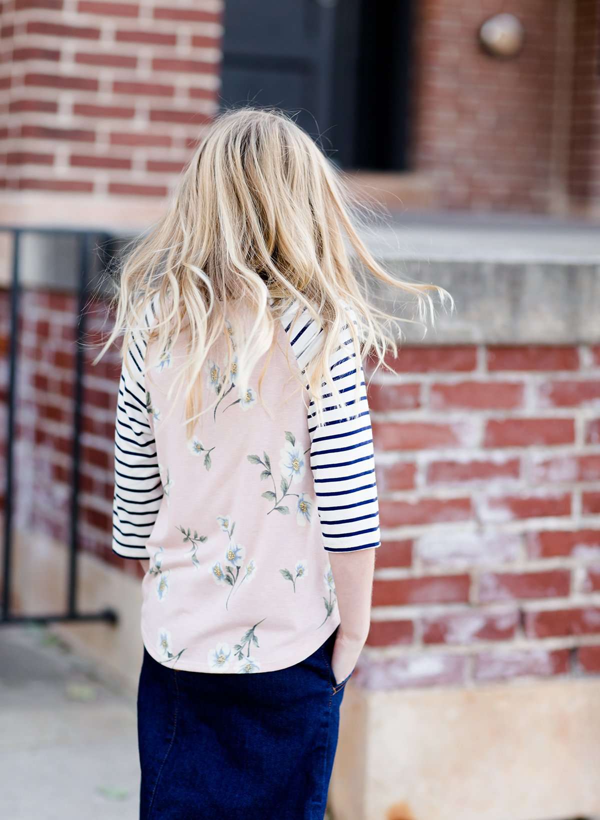 Young girl wearing a floral and striped contrast baseball style modest shirt