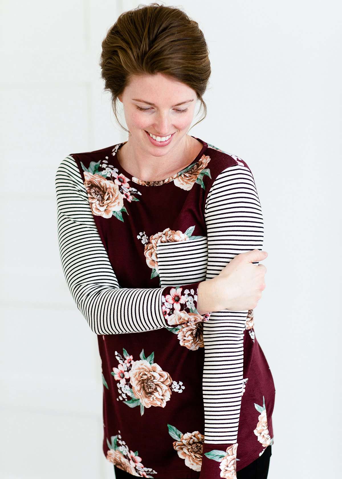 Woman wearing a stripe and floral contrast long sleeve tee with a pocket.